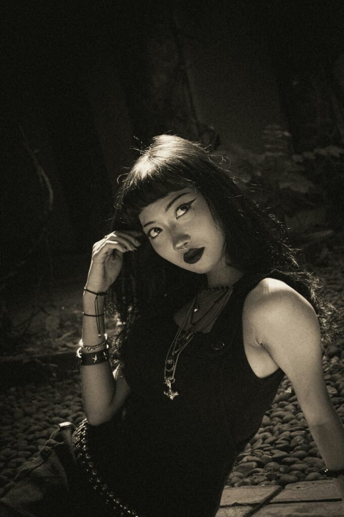 Artistic sepia-toned portrait of a young woman with gothic style in an introspective pose.